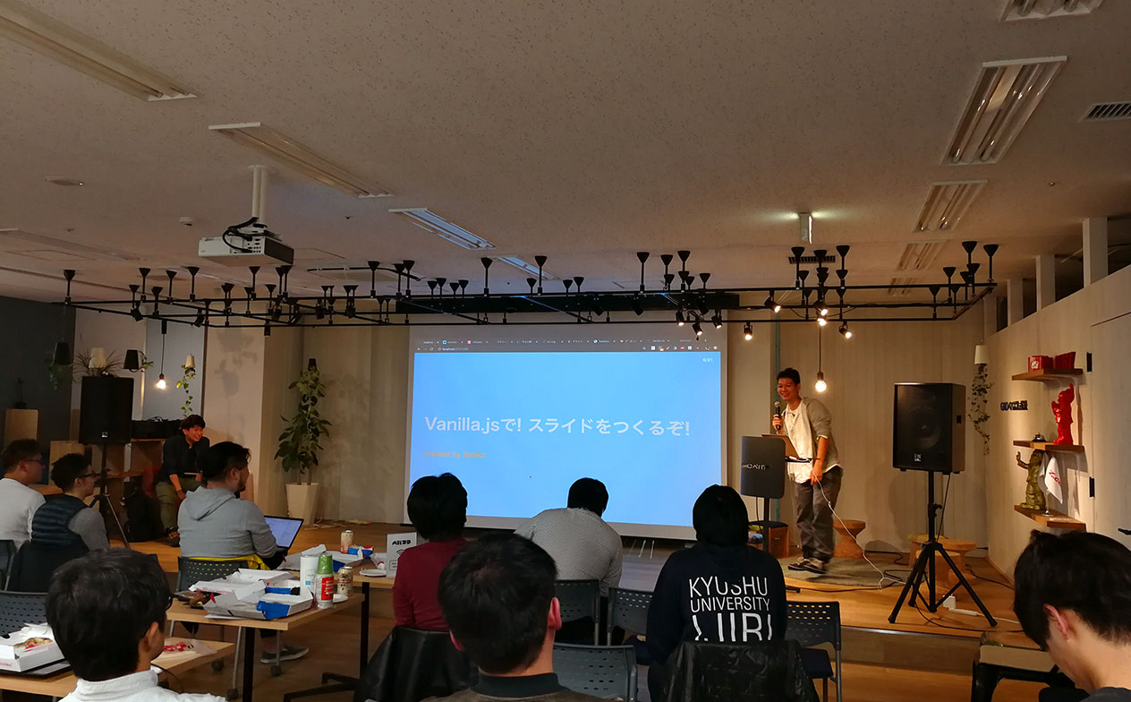 写真：プレゼンテーションを聴いている参加者とピザ